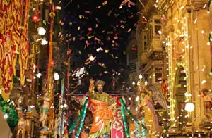 Traditional Maltese Festa celebration with colourful decorations, lights, and confetti.
