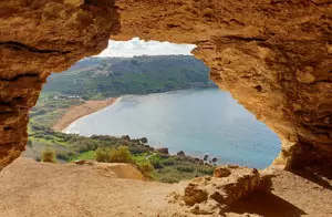 View of Ramla Bay through the natural cave opening at L-Għar tal-Mixta in Gozo, Malta